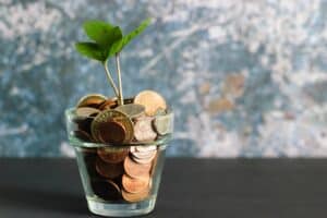 a glass full of coins and a plant growing from it 